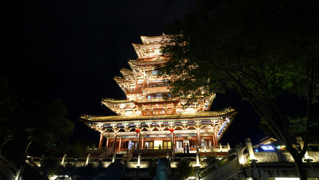 Illuminated multi-tiered traditional Chinese pavilion at night with intricate architectural details