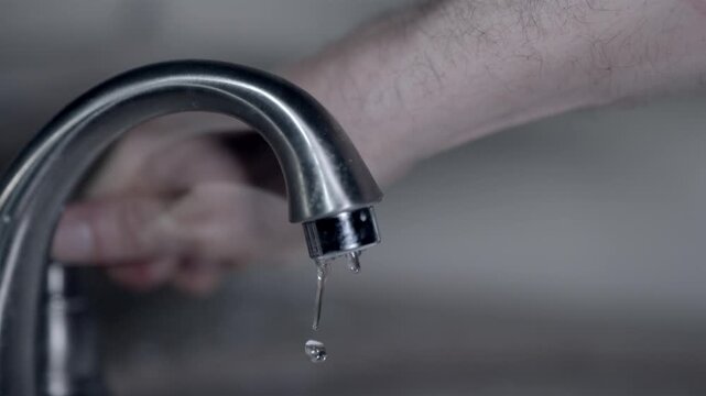 Close up of person gradually turning on the water from a metal faucet