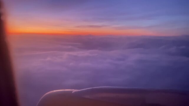 Flying high above the clouds during a colorful sunrise, experiencing a tranquil journey and breathtaking aerial perspective