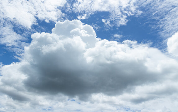 Large fluffy white cumulus cloud in a vibrant blue sky with bright daylight for natural backdrop and weather-themed design
