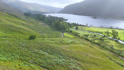Naklejka premium Aerial View of a Misty Loch and Green Valley in Scotland