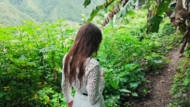 Traveler exploring lush jungle trail touching tree in misty Batad terraces