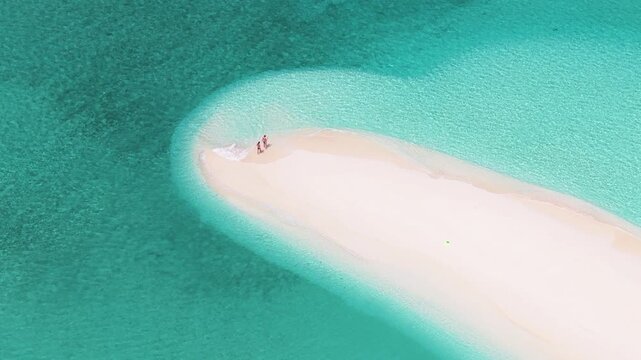Aerial view of a pristine white sandbank surrounded by crystal clear turquoise water with two boats anchored nearby in Vashafaru, Haa Alif, Maldives.