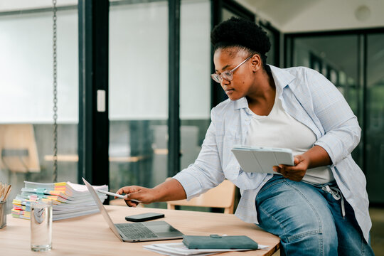Woman working with laptop, tablet, and many documents