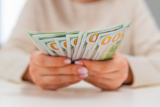 Close up of female hands recounting US dollars. Financial planning, expense control and money management theme.