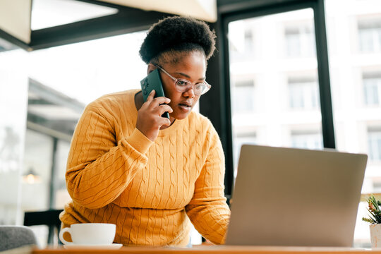 African american woman multitasking with phone and laptop