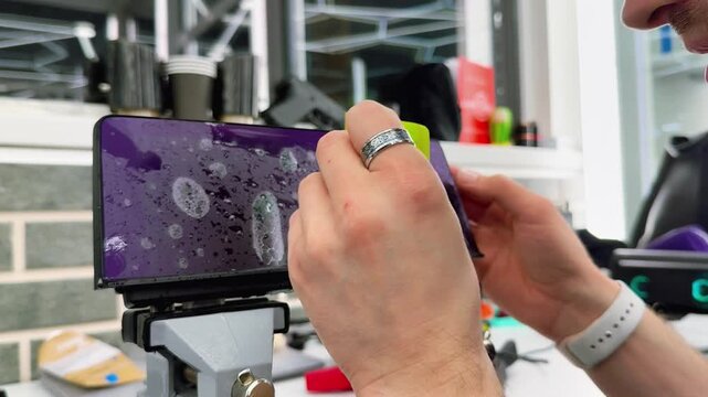 A man wrapping a protective PPF film on a car monitor. The protective glass or film protects the monitor from scratches, fingerprints, other mechanical damage. Wrapping a PPF film to the car display. 