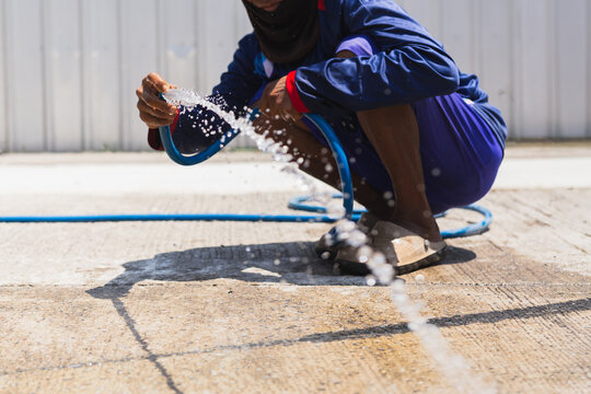 Construction worker wash down concrete surface with a water hose.