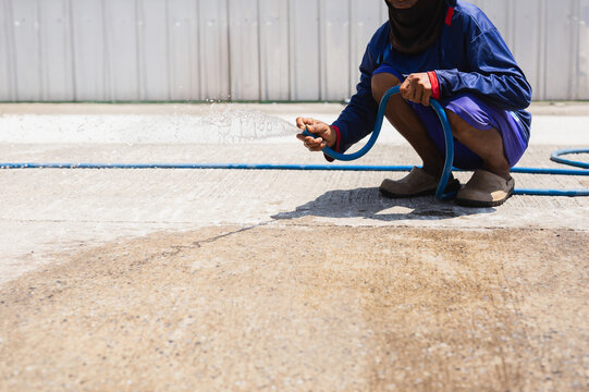 Construction worker wash down concrete surface with a water hose.