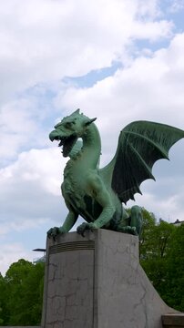 Dragon statue rises on Dragon Bridge in Ljubljana, Slovenia, iconic city landmark, vertical static shot.