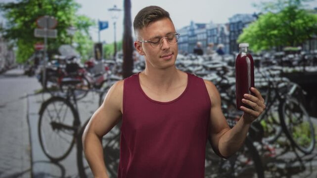 Man holding pomegranate juice bottle pinches nose after sniffing bottle on street; taste test doubt disgust.