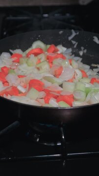 Vertical Footage of Carrots, Onions and Celery on a Skillet 