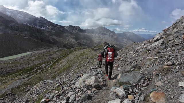 POV hiking with three male mountaineers in Aosta Valley mountains in summer in Pennine Alps, Italy
