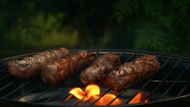 Close-up sausages on bbq grill, cooking hot dogs, slow motion grill fire flame