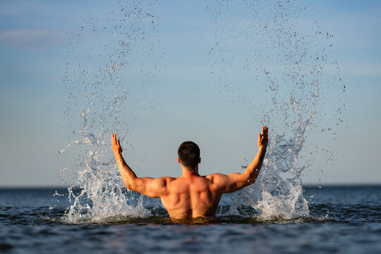 Body model shows muscular wet back. Muscular swimmer pushes body through ocean. Strong body reflects muscular vacation energy. Fresh muscular splashes surround body outdoors.