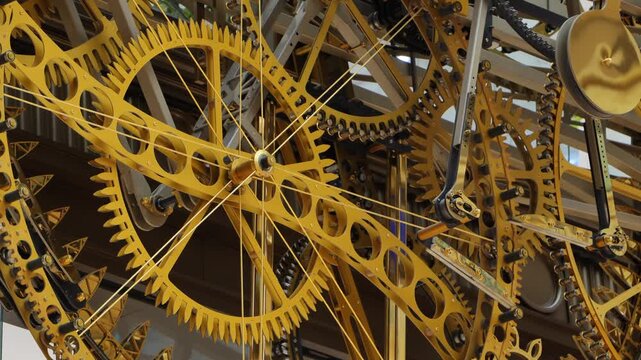 Close-up view of a complex golden clockwork gear mechanism with cogs and chain