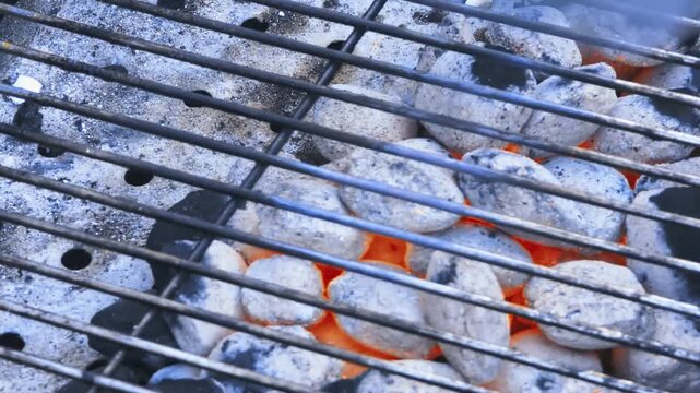 Grilling barbecue briquette coals lit and ready for cooking meat outside in the backyard during summer