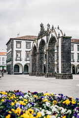 Naklejka premium Historic stone arches in plaza with flowers in foreground