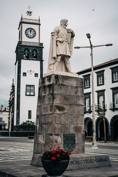 Historic statue with clock tower in European plaza setting