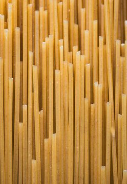 Close up of dry uncooked spaghetti noodles filling frame.