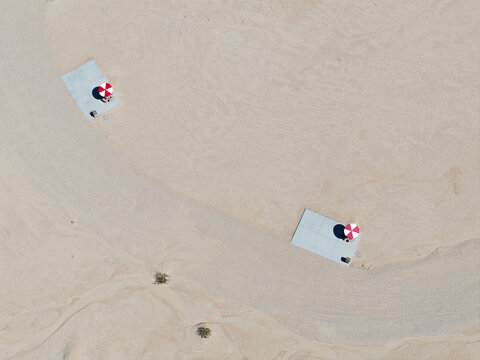 Top down aerial view picnic pads red and white umbrellas in desert