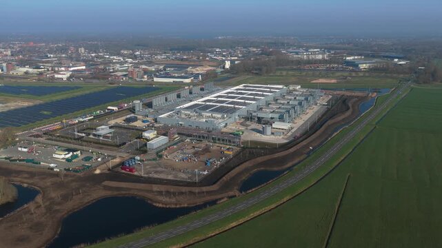 Expansive aerial perspective of a modern ai cloud computing data center under construction, adjacent to a large solar farm in winschoten, netherlands