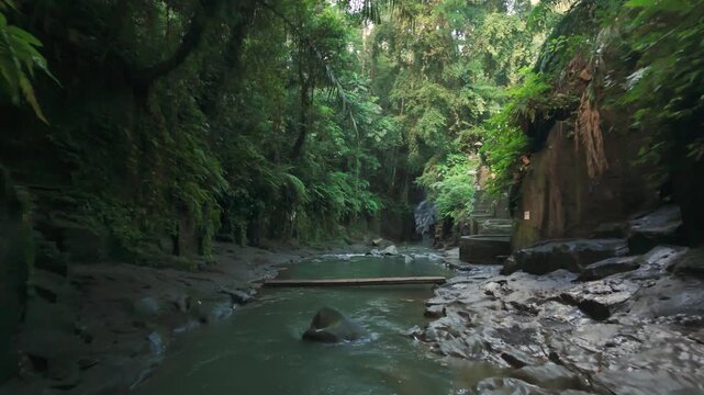 Drone flight follows a flowing stream through the tropical jungle near Tukad Beng Canyon in Bali.