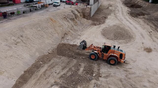 Front loader moving earth in large excavation pit at construction site