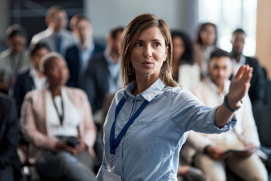 Speaker, woman and speech to audience in presentation for insight, coaching or wealth management. Global seminar, business crowd or keynote address for industry trends, learning or financial literacy