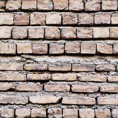 Obraz premium close-up view of old bricks arranged in a rough wall pattern showing weathered texture earthy tones and natural imperfections that highlight construction materials and rustic architectural surfaces.