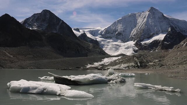 A view of iceberg filled glacial lake of Glacier de Cheilon with the mountain peaks of the Swiss Alps sunlit on a summer day