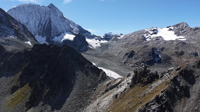 Aerial flyover over the cliffs next to Glacier de Cheilon near Arolla, Switzerland with a view of a hiking trail leading to the Pas de Chevre ridge and peaks such as Mont Blanc de Cheilon