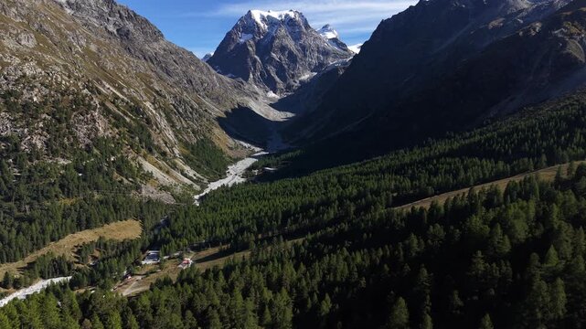 Aerial flyover above the forest near Arolla, Switzerland with a view of the Mont Collon in the background on a sunny summer day in the Swiss Alps