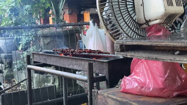 raditional charcoal grill for satay with glowing red embers and smoke, street food preparation concept