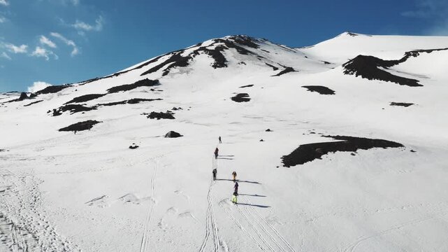 Aerial view of Rifugio Sapienza on Mount Etna with skiers trekking across the snow-covered volcanic slopes Nicolosi, Sicilia, Italy.