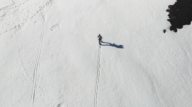 Aerial view of a person ski touring on the white snow slopes near Rifugio Sapienza with long shadows and ski tracks in Nicolosi, Sicilia, Italy.