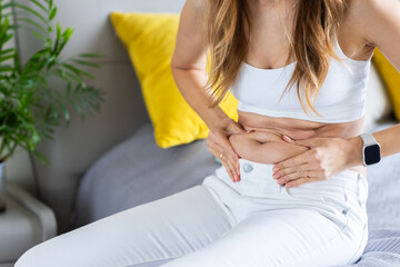 Fototapeta premium Young woman examining her midsection at home