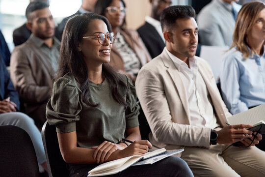 Businesswoman, laugh and audience in seminar for presentation, notes and wealth management training. Workshop, team and happy people with notebook for speech, learning or financial development skills