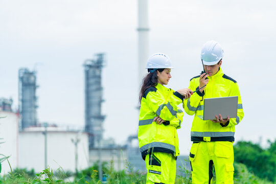 Petroleum refinery engineers and industrial worker working on laptop, inspection oil refinery plant at construction site with radio communication, technician teamwork maintaining energy power system