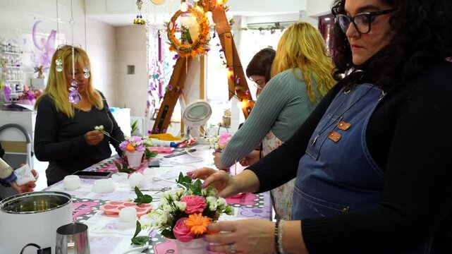 Group of female artisans creating decorative handmade candles with flowers during a creative class