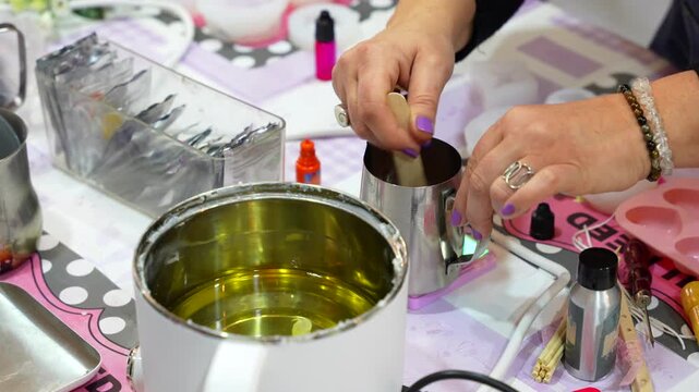 Artisan melting and stirring soy wax to create handmade scented candles in a workshop