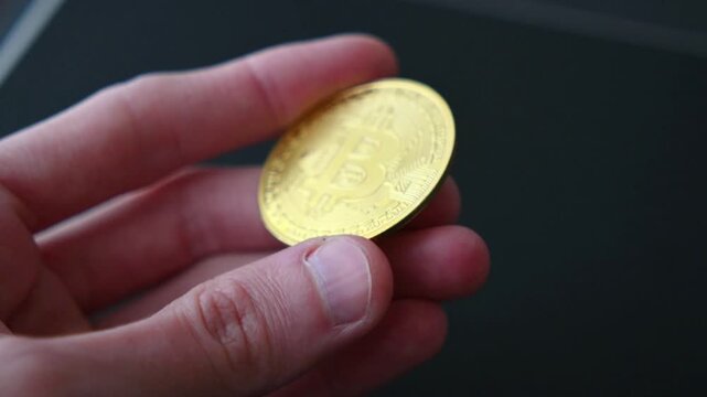Golden bitcoin coin on dark textured surface shows cryptocurrency logo