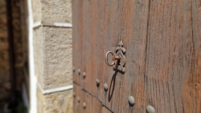 Old metal key unlocking a rustic wooden door with iron studs