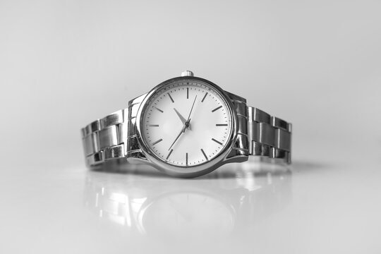 Minimalist Silver Analog Wristwatch on Reflective White Surface