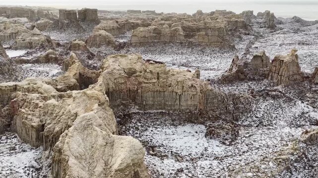 Aerial view of the unique salt formations and rugged geological structures of the Danakil Desert under a hazy sky in Dalol, Afar, Ethiopia.
