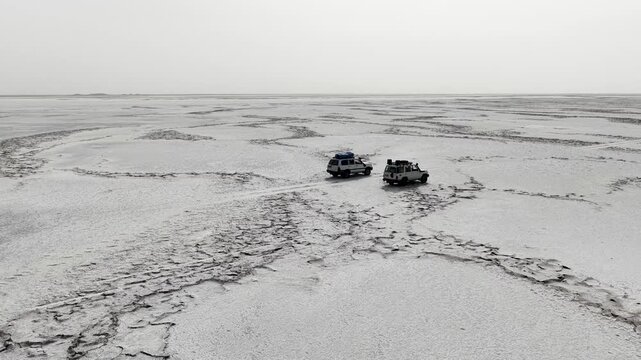 Aerial view of two off-road vehicles crossing the cracked salt plains of the Danakil Desert Dalol, Afar, Ethiopia.