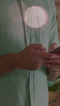 Vertical video: Man holding phone tapping thumbs, starting scrolling for tech bokeh across hands
