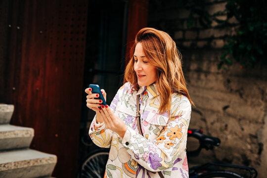 Stylish millennial female checking mobile phone on urban street