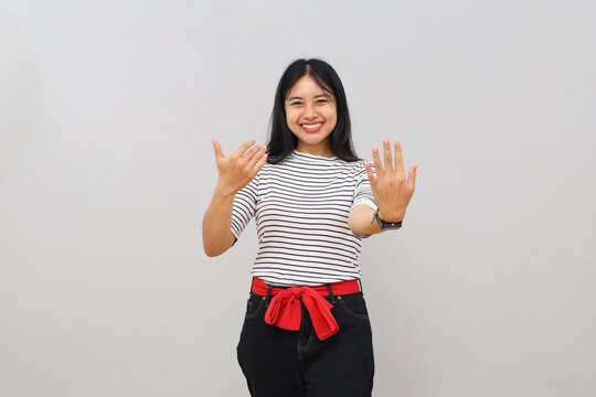 A young woman uses a hand gesture to call "come here" with her palms outstretched in a welcoming pose, a cheerful expression, isolated on a white background.