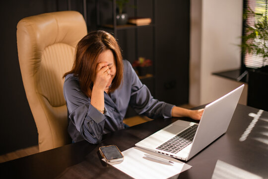 Exhausted female office worker feeling tired and overwhelmed during working day
